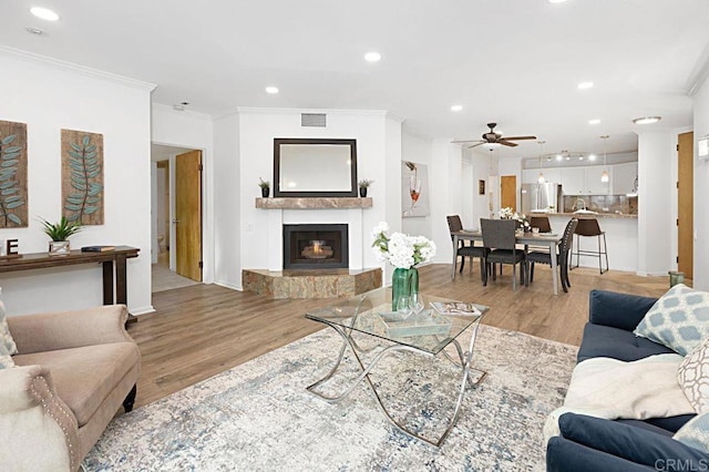 living room featuring crown molding, ceiling fan, and light wood-type flooring