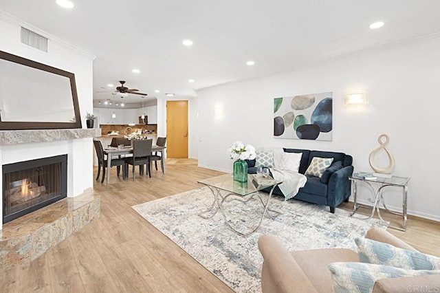 living room featuring crown molding, ceiling fan, and light hardwood / wood-style floors