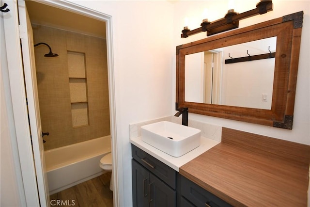 full bathroom featuring vanity, hardwood / wood-style floors, tiled shower / bath combo, and toilet