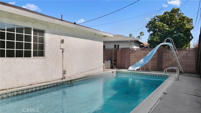 view of swimming pool with a fenced in pool, fence, and a water slide