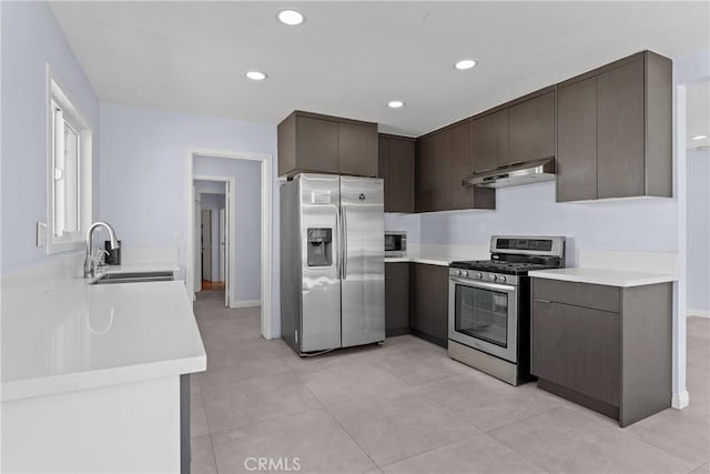 kitchen featuring under cabinet range hood, a sink, dark brown cabinets, appliances with stainless steel finishes, and light countertops