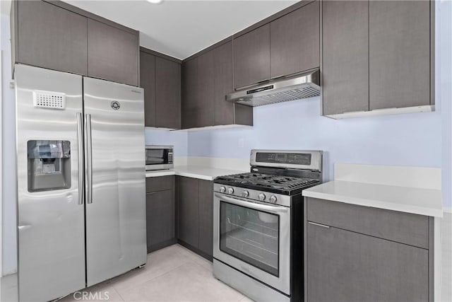 kitchen featuring light tile patterned floors, under cabinet range hood, stainless steel appliances, dark brown cabinets, and light countertops