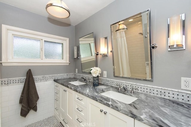 bathroom featuring double vanity, tile walls, a tile shower, and a sink