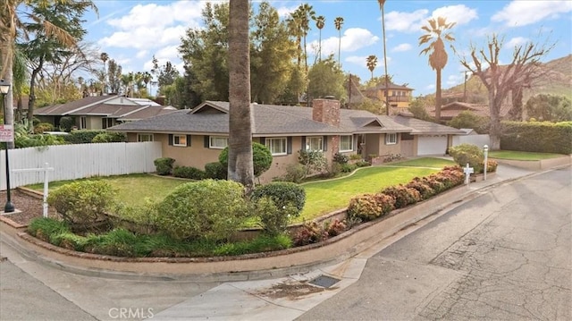 ranch-style house featuring a garage, a chimney, fence, a front yard, and stucco siding