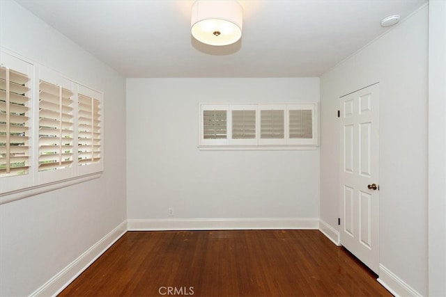 spare room with baseboards and wood finished floors