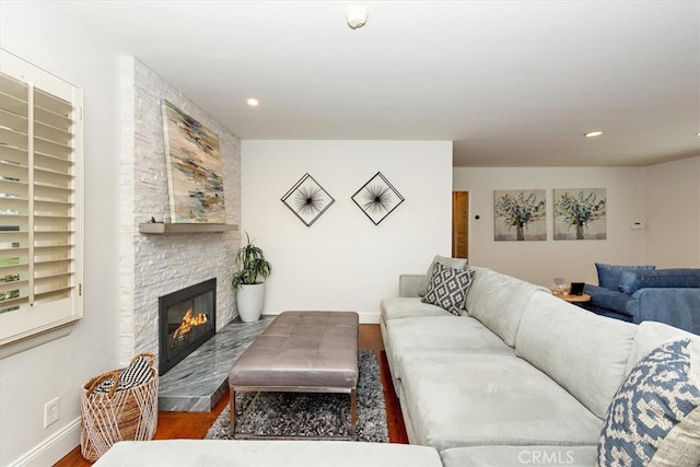 living room featuring a fireplace, baseboards, wood finished floors, and recessed lighting