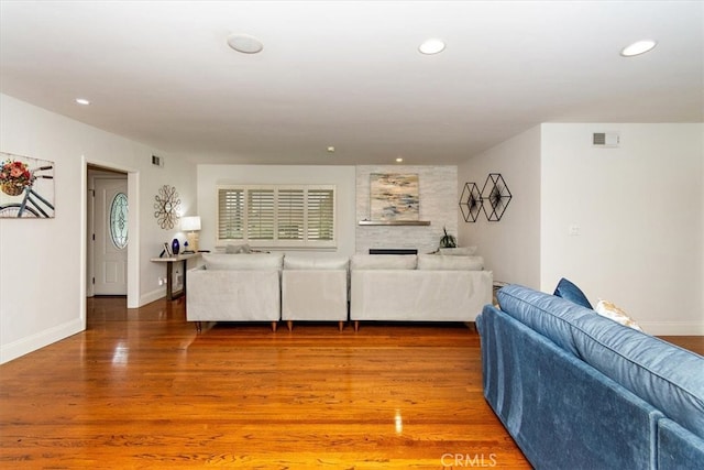 living area with baseboards, visible vents, wood finished floors, and recessed lighting