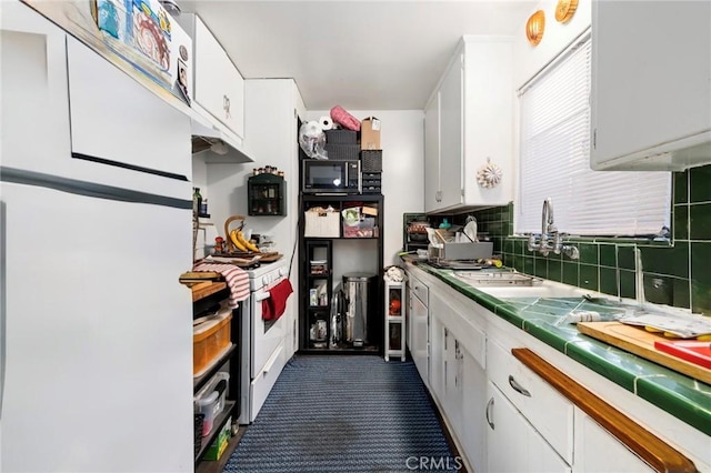 kitchen featuring white appliances, tile countertops, decorative backsplash, and white cabinets