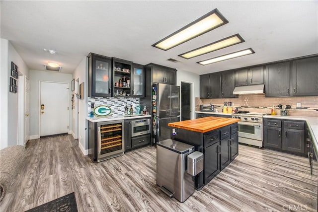 kitchen with wine cooler, decorative backsplash, light hardwood / wood-style flooring, and stainless steel appliances