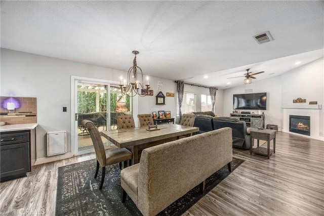 dining space featuring vaulted ceiling, ceiling fan with notable chandelier, and light wood-type flooring