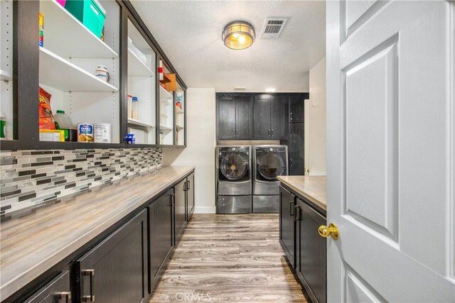 laundry area featuring cabinets, washing machine and dryer, and light wood-type flooring