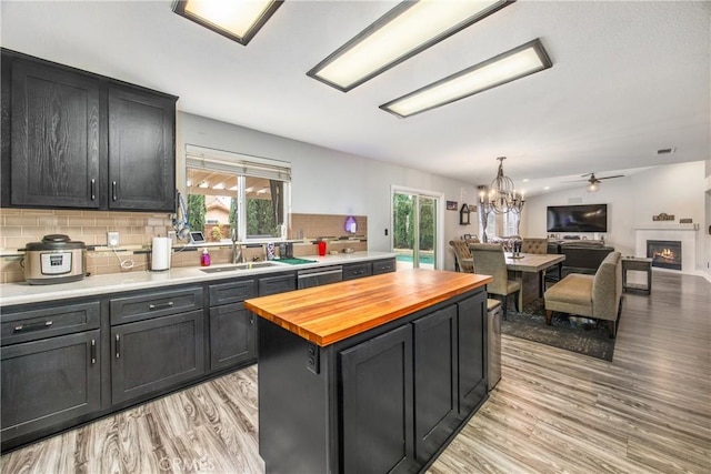 kitchen featuring butcher block countertops, tasteful backsplash, sink, a center island, and light hardwood / wood-style floors