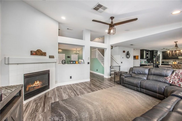 living room featuring hardwood / wood-style flooring, a fireplace, and ceiling fan with notable chandelier