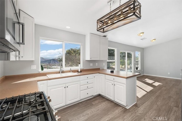 40350 Exa Ely Rd, Hemet, CA 92544 - kitchen with a sink, gas range oven, stainless steel microwave, a peninsula, and white cabinetry