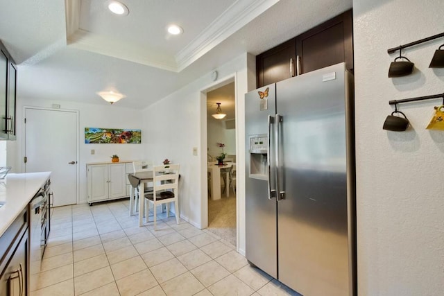 kitchen featuring light tile patterned flooring, ornamental molding, stainless steel fridge with ice dispenser, a raised ceiling, and dark brown cabinets