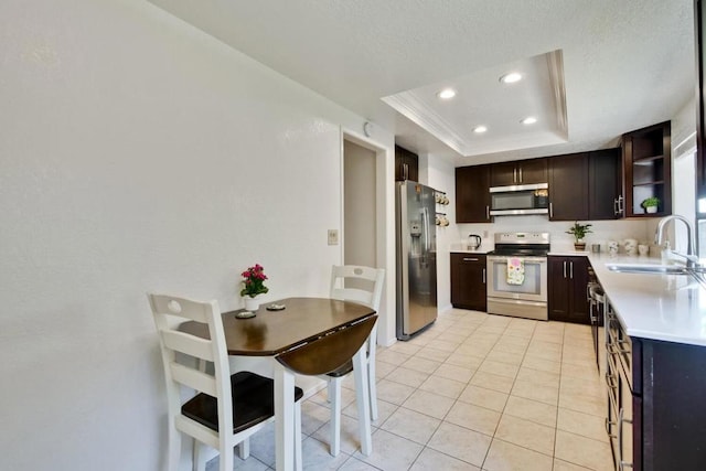 kitchen with appliances with stainless steel finishes, sink, light tile patterned floors, a raised ceiling, and dark brown cabinets