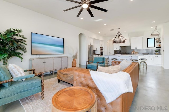 living room with ceiling fan with notable chandelier