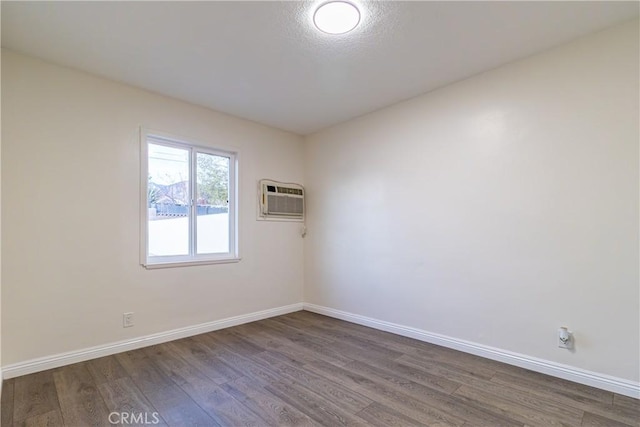 spare room featuring hardwood / wood-style floors and a wall mounted air conditioner