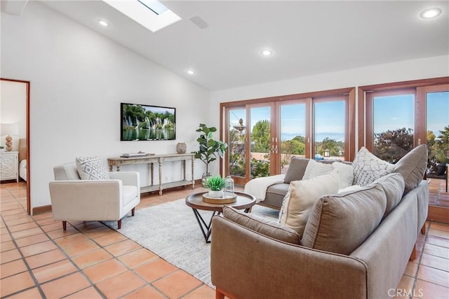 tiled living room featuring high vaulted ceiling and a skylight