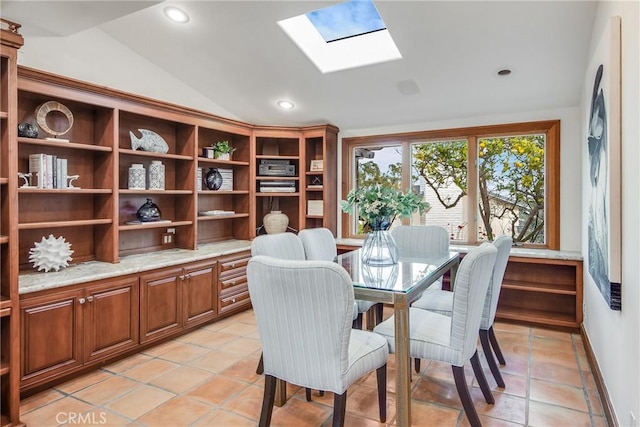 tiled dining area with vaulted ceiling with skylight