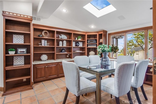 tiled dining area with lofted ceiling with skylight