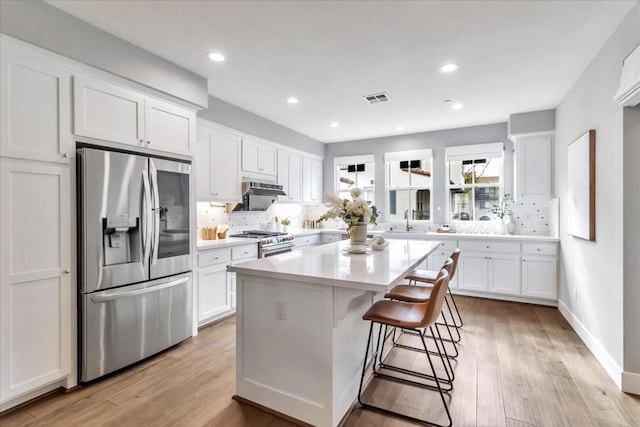 kitchen featuring sink, white cabinetry, tasteful backsplash, appliances with stainless steel finishes, and a kitchen island