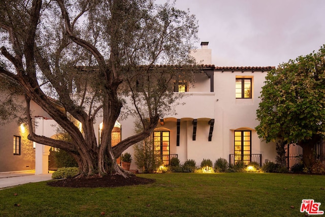 mediterranean / spanish house with french doors and a front lawn