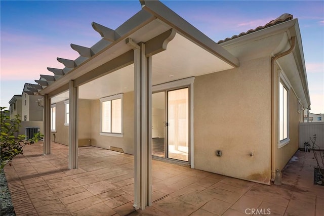 back house at dusk featuring cooling unit and a patio area