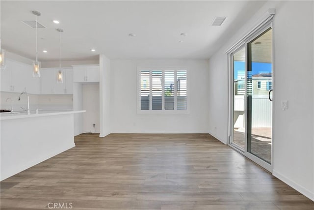 unfurnished living room with light hardwood / wood-style flooring and sink