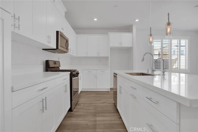 kitchen with appliances with stainless steel finishes, decorative light fixtures, sink, and white cabinetry