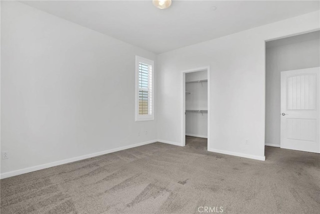 unfurnished bedroom with a closet, a walk in closet, and carpet flooring