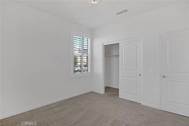 unfurnished bedroom featuring light carpet and a closet