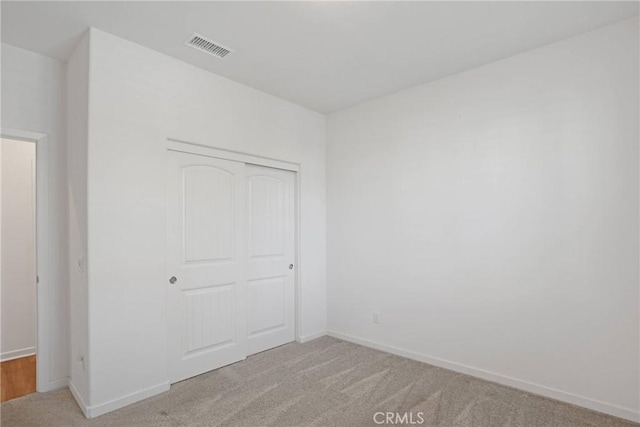 unfurnished bedroom featuring a closet and light colored carpet