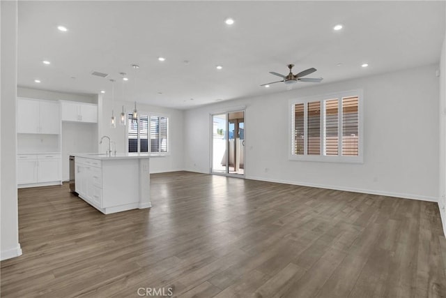 unfurnished living room featuring dark hardwood / wood-style flooring, ceiling fan, and sink