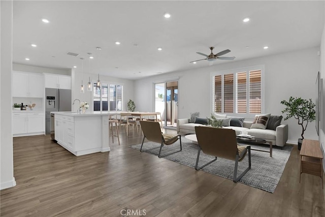 living room featuring ceiling fan, sink, and dark wood-type flooring