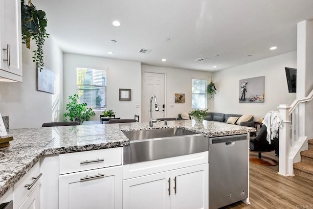 kitchen featuring sink, white cabinetry, light hardwood / wood-style flooring, dishwasher, and light stone countertops