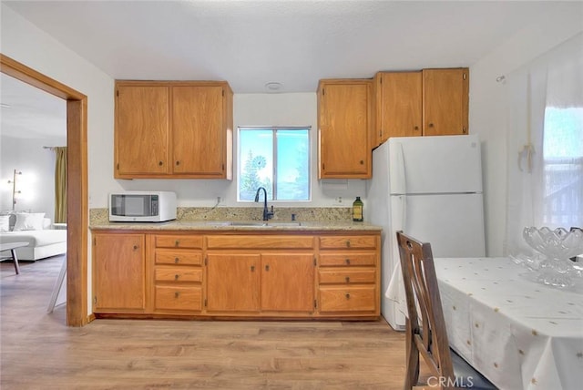 kitchen with sink, white appliances, and light wood-type flooring