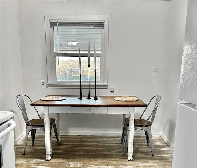 dining space with baseboards and wood finished floors