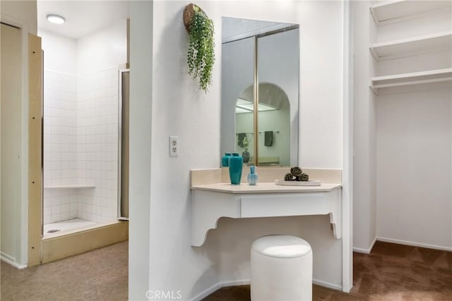 bathroom featuring a tile shower and vanity