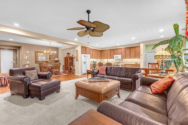 living room with ceiling fan with notable chandelier and light hardwood / wood-style floors