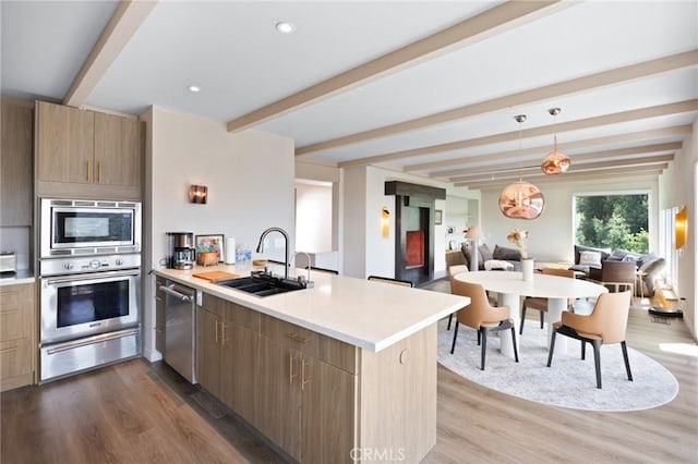 kitchen with beam ceiling, a warming drawer, stainless steel appliances, a sink, and a peninsula