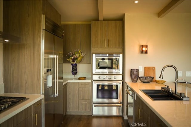 kitchen with beamed ceiling, built in appliances, a sink, light countertops, and a warming drawer