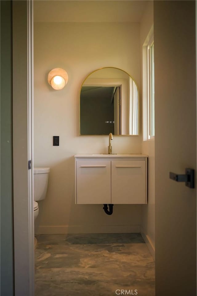 bathroom with toilet, baseboards, and vanity