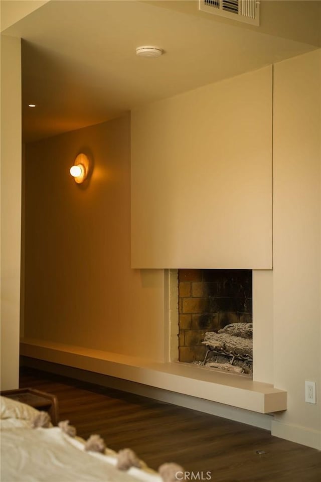 details with baseboards, a fireplace, visible vents, and wood finished floors