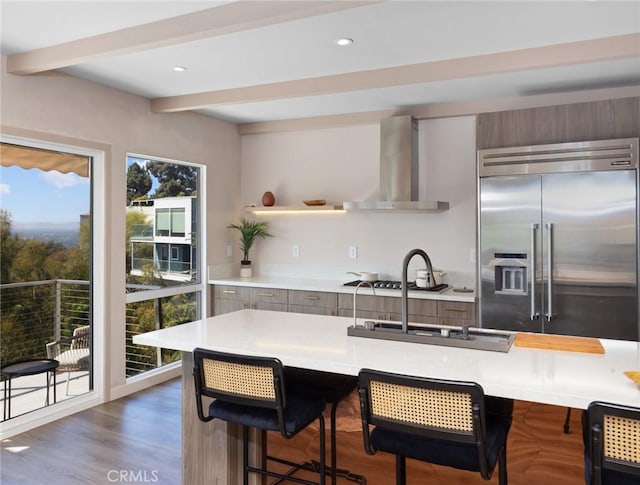 kitchen featuring built in fridge, beam ceiling, light countertops, modern cabinets, and wall chimney exhaust hood