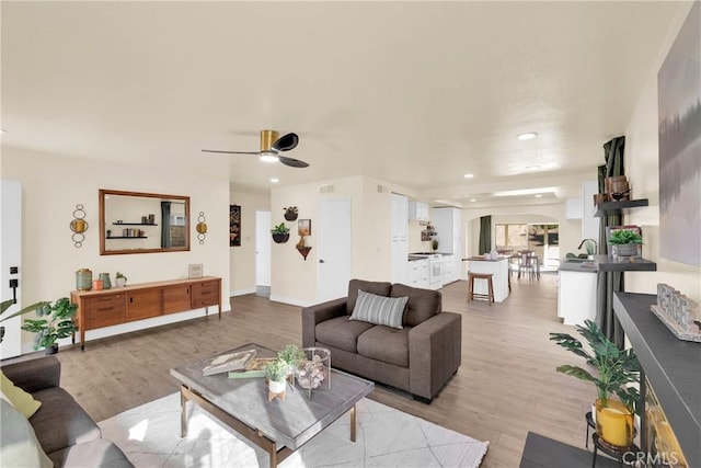 living room featuring ceiling fan, recessed lighting, baseboards, and light wood-style floors