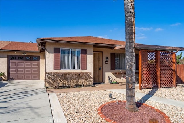 view of front of home featuring driveway, an attached garage, and stucco siding