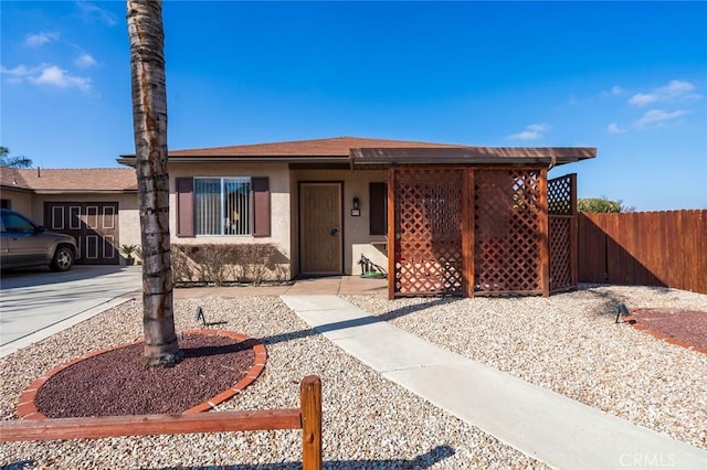 view of front facade featuring concrete driveway, fence, and stucco siding