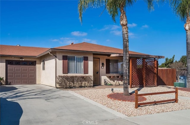 ranch-style home with a garage, driveway, fence, and stucco siding