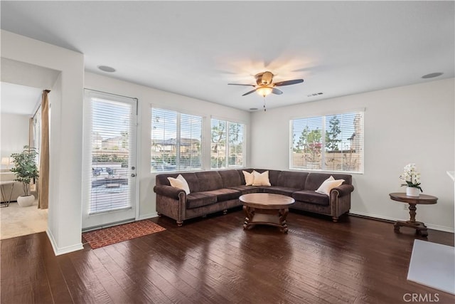 living room featuring hardwood / wood-style flooring, baseboards, visible vents, and a ceiling fan